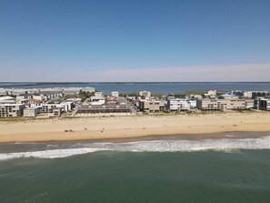 A coastal beach area with a row of buildings along the shore. - Modern 4BR Ocean Block Apt, Walk to the Beach (Ocean City)