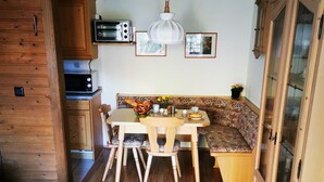 A cozy kitchen with wooden cabinets, a dining table with chairs, and a bench. - Wohnung 06 (Berchtesgaden)