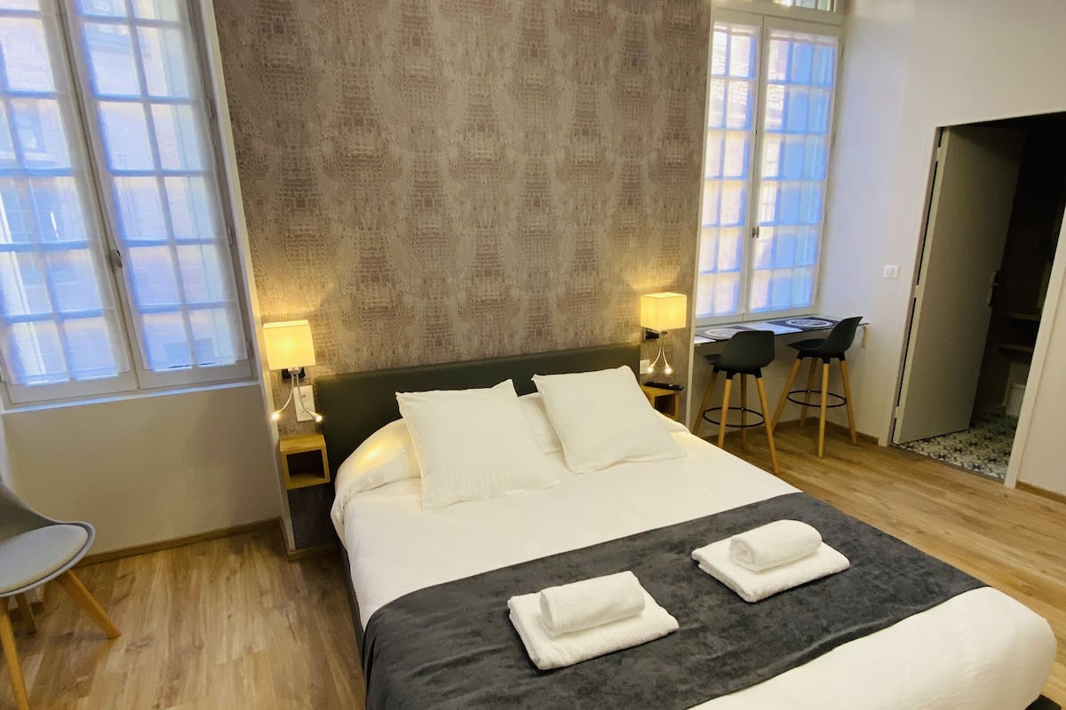 Een moderne hotelkamer met een groot bed, twee bedlampen, een bureau en een stoel.