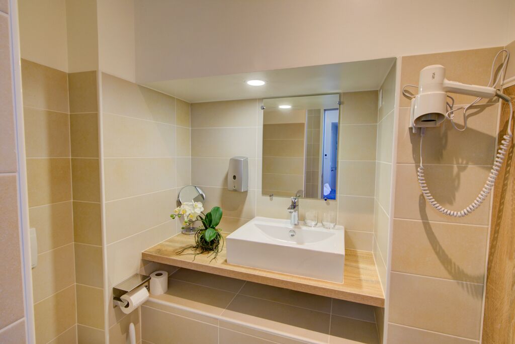 A bathroom with a sink, mirror, and hairdryer.