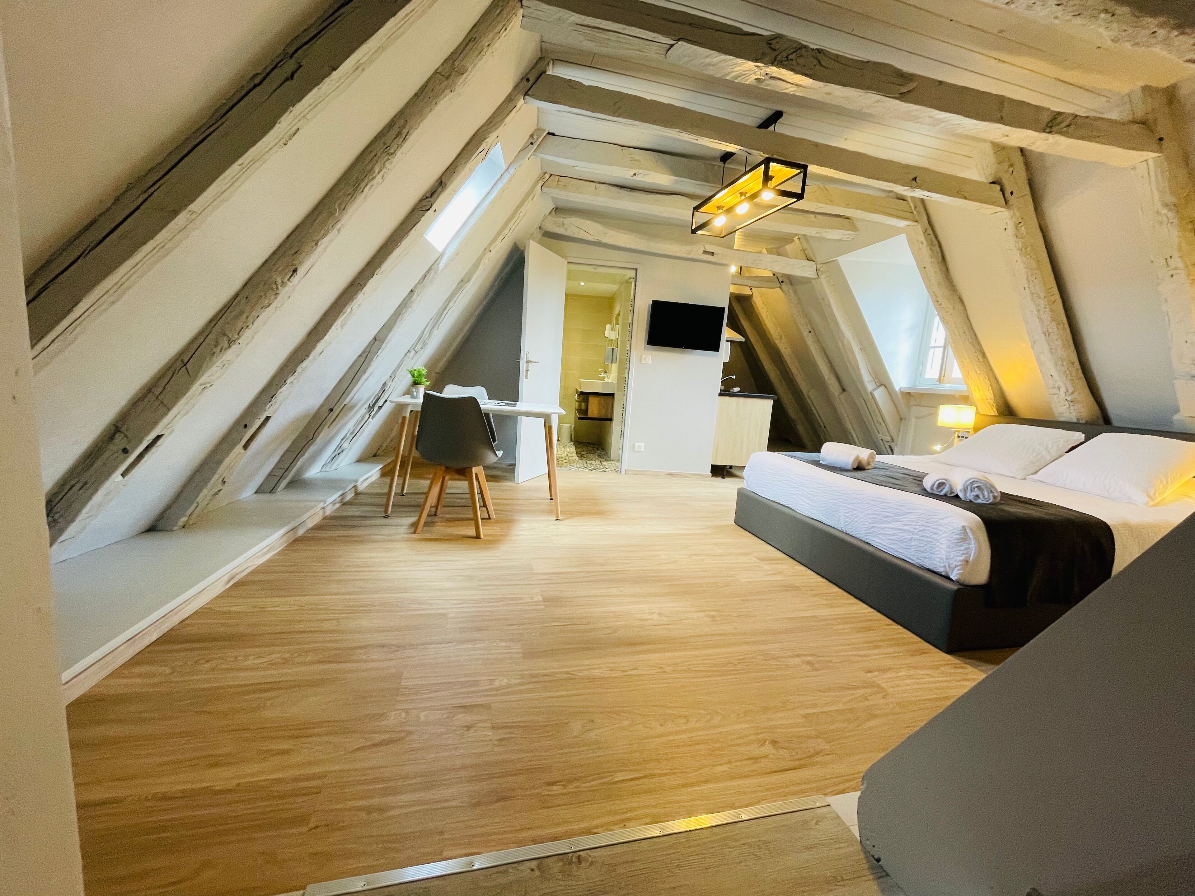 Un dormitorio con cama, escritorio y silla en una habitación con techo inclinado.