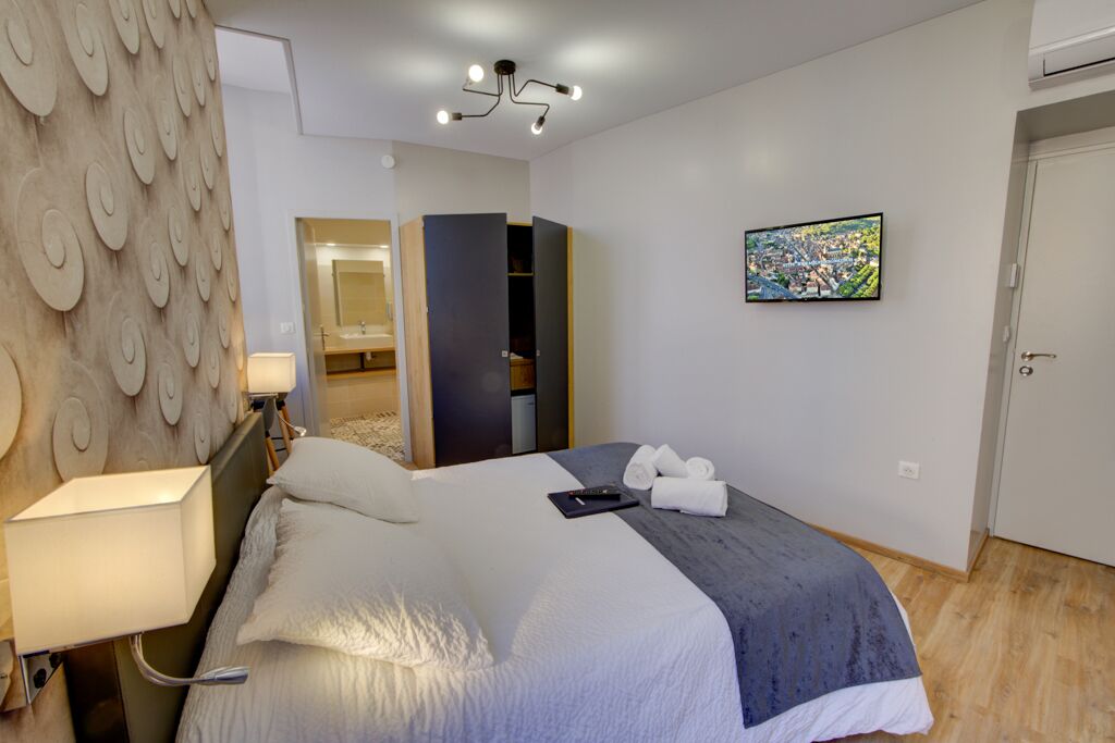 Una habitación de hotel moderna con cama, lámpara de noche, armario y un cuadro en la pared.