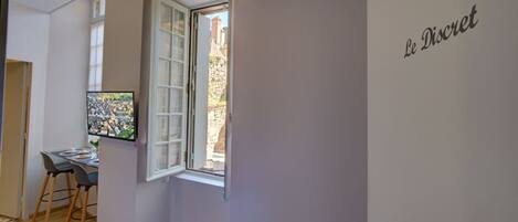A room with a large window, a desk with a computer, and a chair.