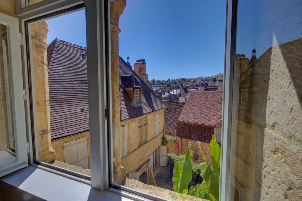 A view from a window overlooking a historic town with stone buildings and a clear sky.