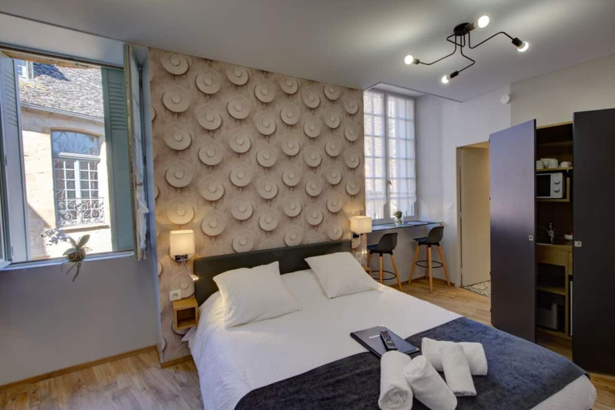 Een moderne slaapkamer met een groot bed, een bureau en een kledingkast.