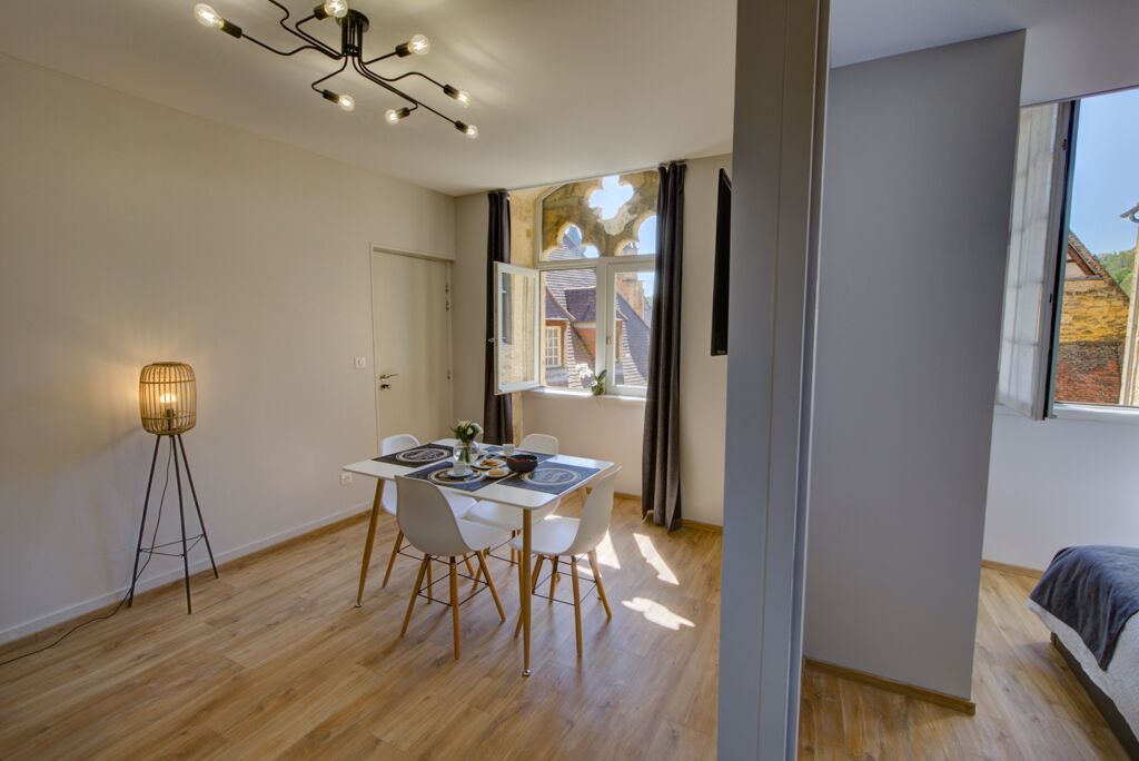 Una habitación moderna con comedor, una lámpara de pie y un amplio ventanal con cortinas.