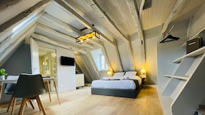 Een moderne loft slaapkamer met een schuine plafond, een bed, een bureau en een stoel.