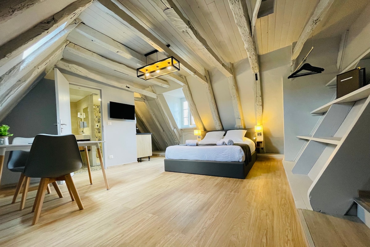 Een moderne loft slaapkamer met een schuine plafond, een bed, een bureau en een stoel.