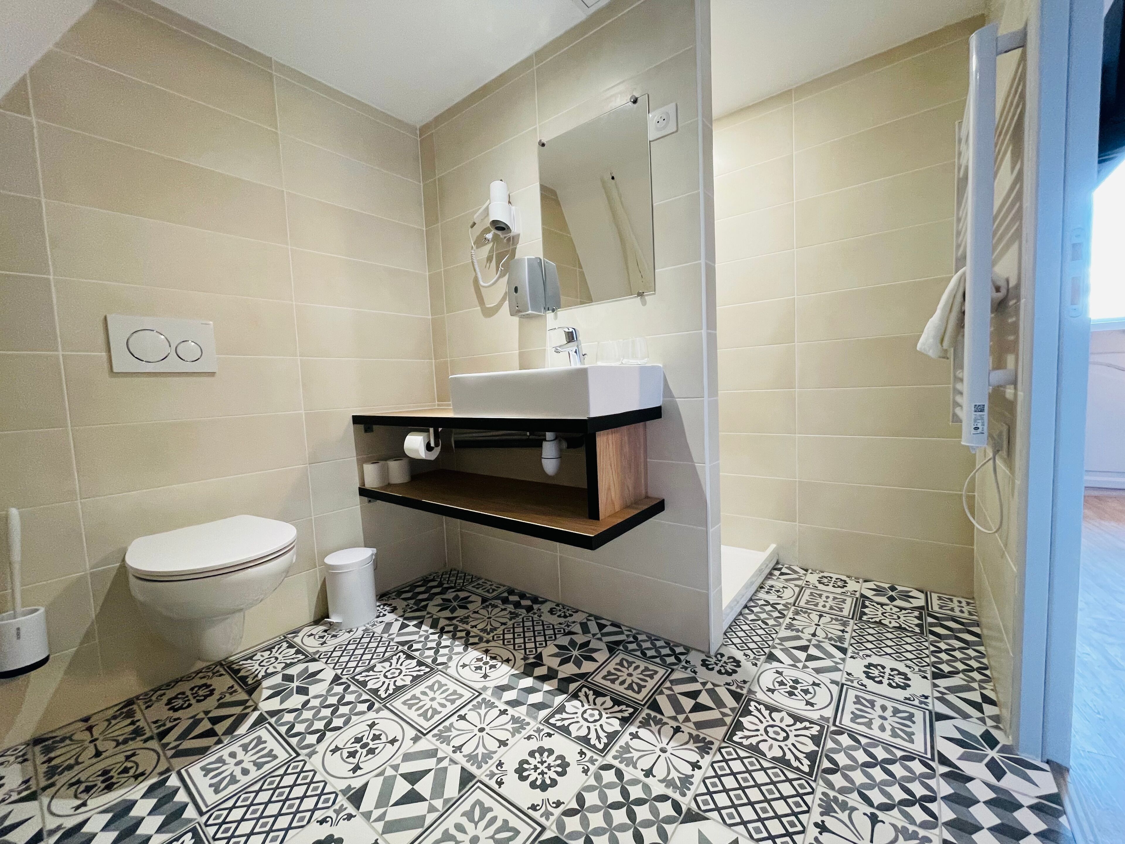 A bathroom with a toilet, sink, and mirror. The floor has patterned tiles.