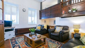 A living room with a sofa, chairs, a coffee table, a TV, and a bookshelf. - Capel Bach  -  a near a pub that sleeps 6 guests  in 3 bedrooms (Llanystumdwy)