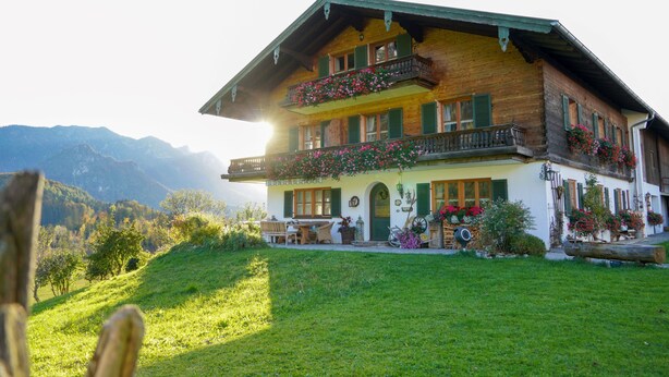 Eine Holzchalet mit Balkon, Essbereich und einem Blumenblumenbehang.