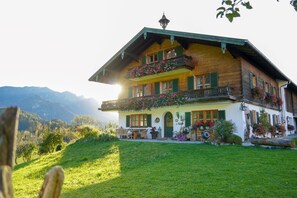 Eine Holzchalet mit Balkon, Essbereich und einem Blumenblumenbehang.