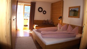Ein Schlafzimmer mit Holzboden, einem großen Bett, einem Holz-Kopfteil, einem Nachttisch und einer Wandlampe.