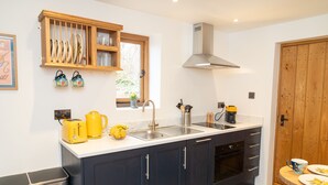 A modern kitchen with dark cabinets, a stainless steel sink, and a wooden door.