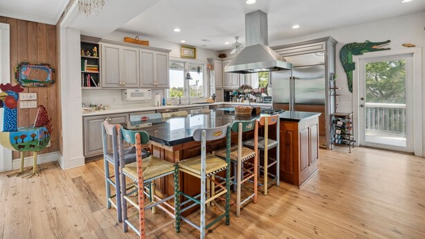 Una cocina amplia con armarios de madera, una isla grande con taburetes y vistas al exterior.