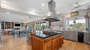 Una cocina amplia con una isla grande, armarios de madera y una estufa moderna.