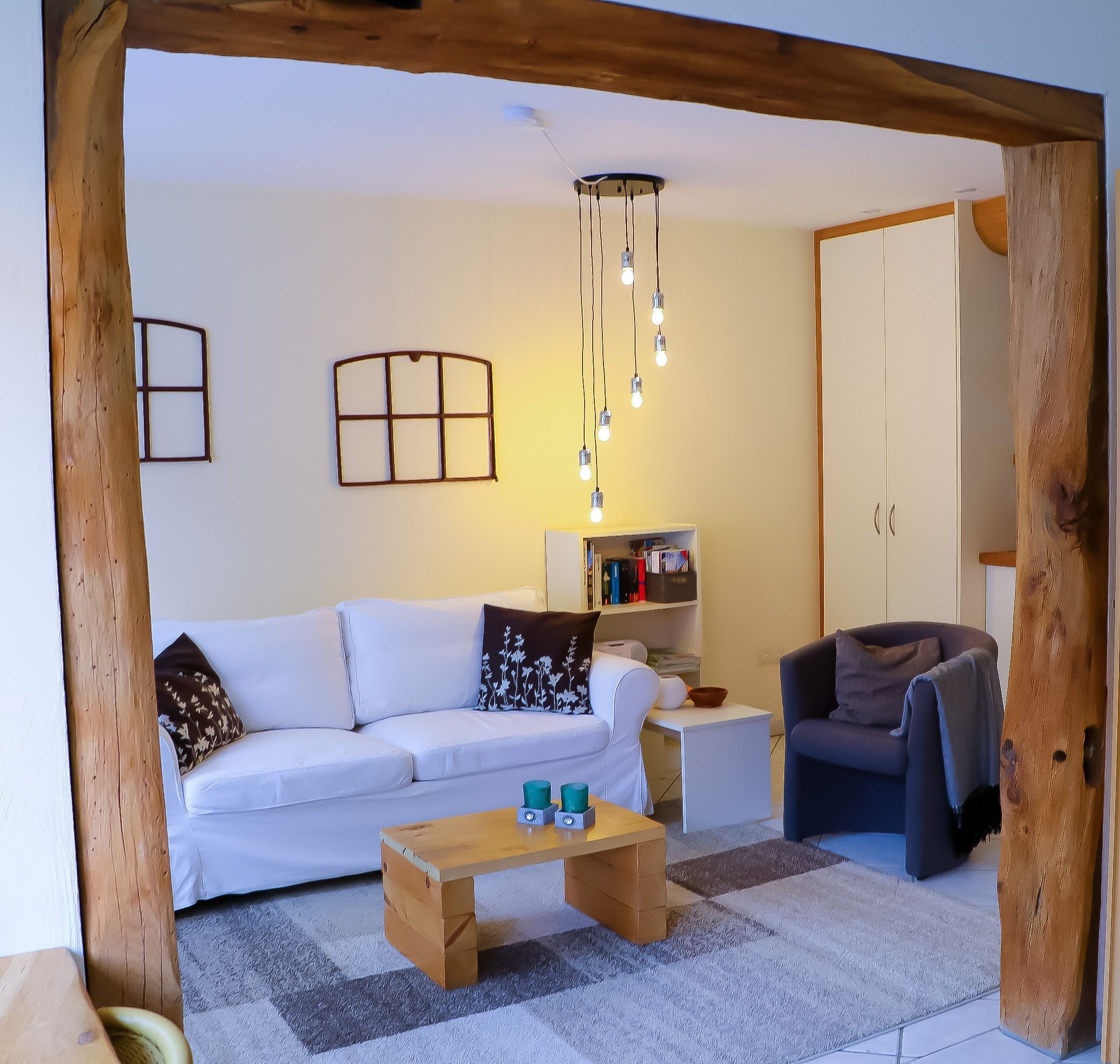 A living room with a white sofa, a wooden coffee table, a bookshelf, and a cabinet.