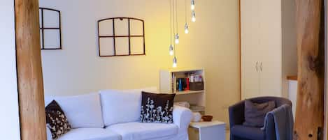 A living room with a white sofa, a wooden coffee table, a bookshelf, and a cabinet.