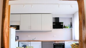A modern kitchen with white cabinets, a built-in oven, and a dining area with a wooden table and chairs.