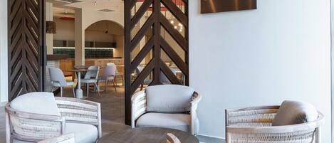 A modern lounge area with wicker furniture and a sign reading "MADRE".