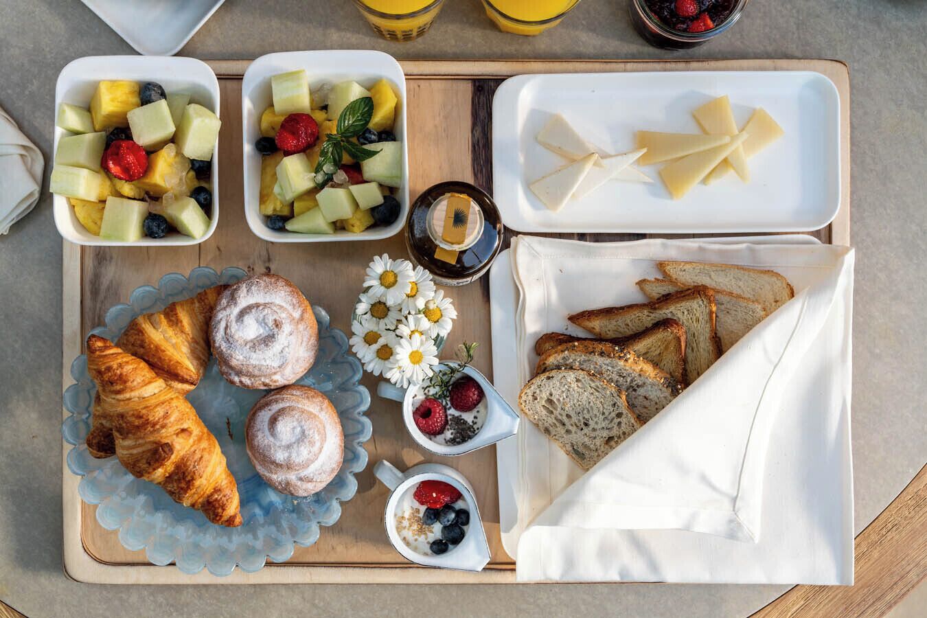Bandeja de desayuno con cruasanes, fruta, queso y pan.