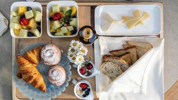 Een ontbijtplateau met croissants, fruit, kaas en brood.