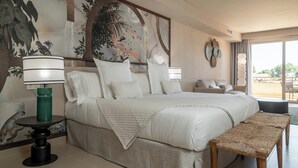 Un dormitorio amplio con una cama grande, una mesita de noche, un banco y vistas al exterior.
