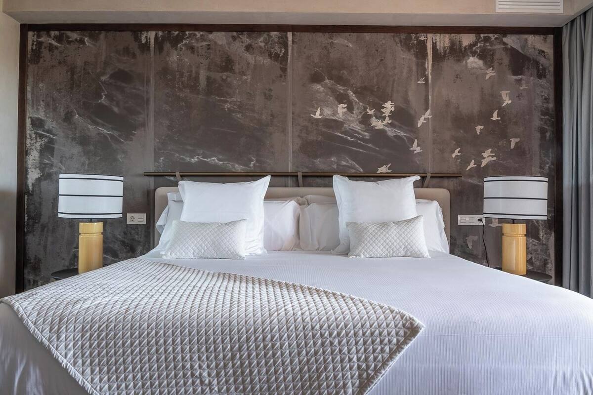 Ein Hotelzimmer mit einem großen Bett, zwei Nachttischlampen und einer strukturierten Wand.