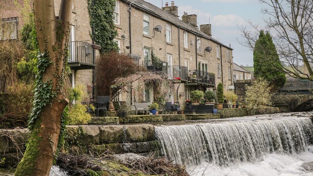 A stone building with a waterfall in front. - Bear Pit Cottage (High Peak)