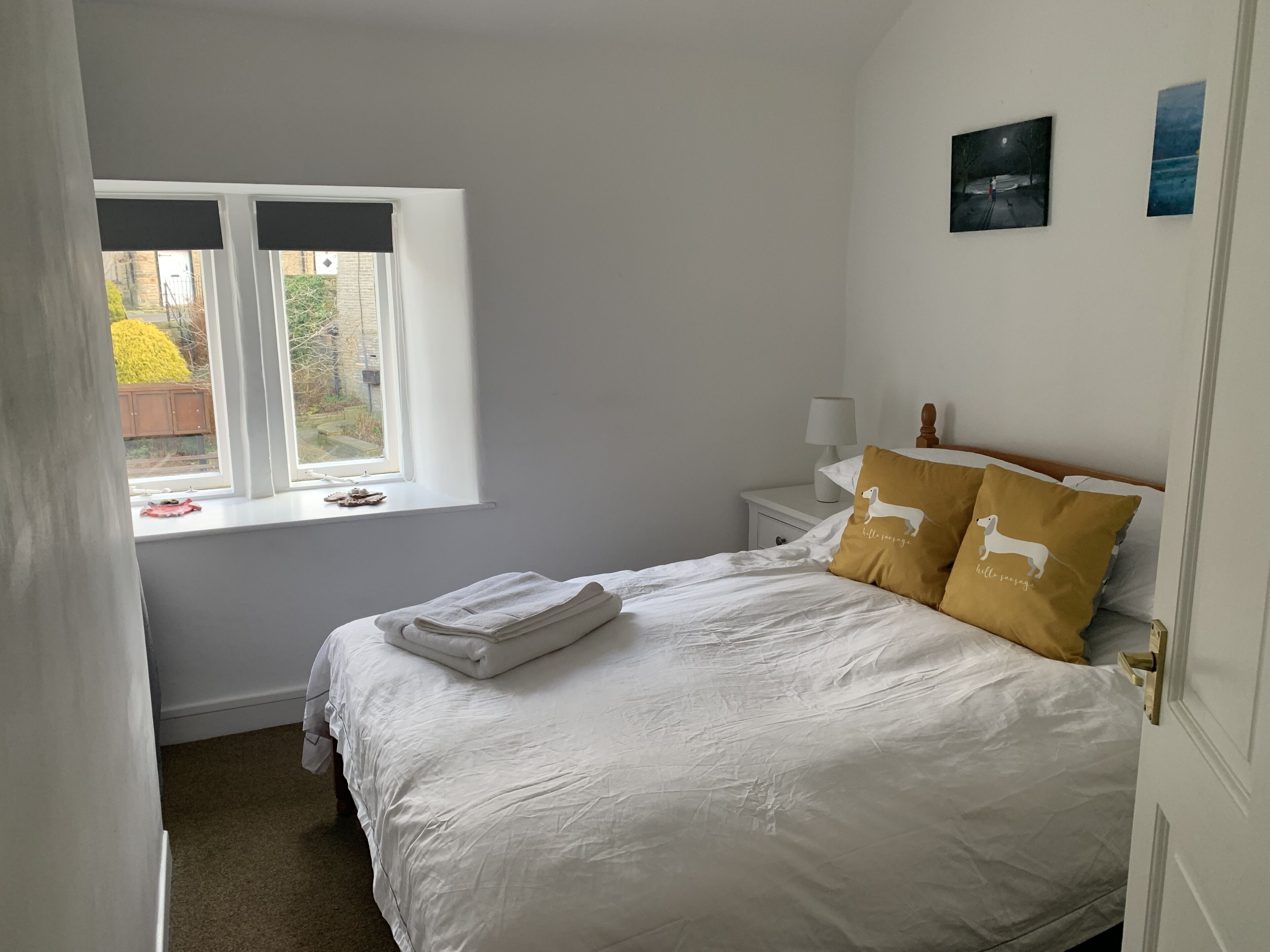 A bedroom with a bed, a nightstand, a window, and a door.