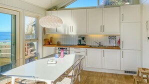 Una cucina moderna con mobili bianchi, un piano di lavoro in legno e una grande isola con sgabelli da bar.