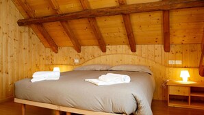 A wooden-paneled bedroom with a bed, bedside tables, and a lamp. - Stunning private villa for 4 people with WIFI and TV (Ovaro)
