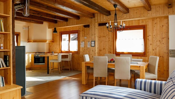 A cozy wooden cabin interior with a dining area, kitchen, and a living room with a sofa and a coffee table. - Stunning private villa for 4 people with WIFI and TV (Ovaro)