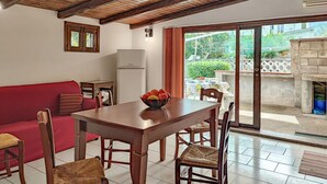 A dining area with a wooden table and chairs, a red sofa, and a bowl of fruit on the table. - 2 bedroom beautiful home in Torrenova (Torrenova)