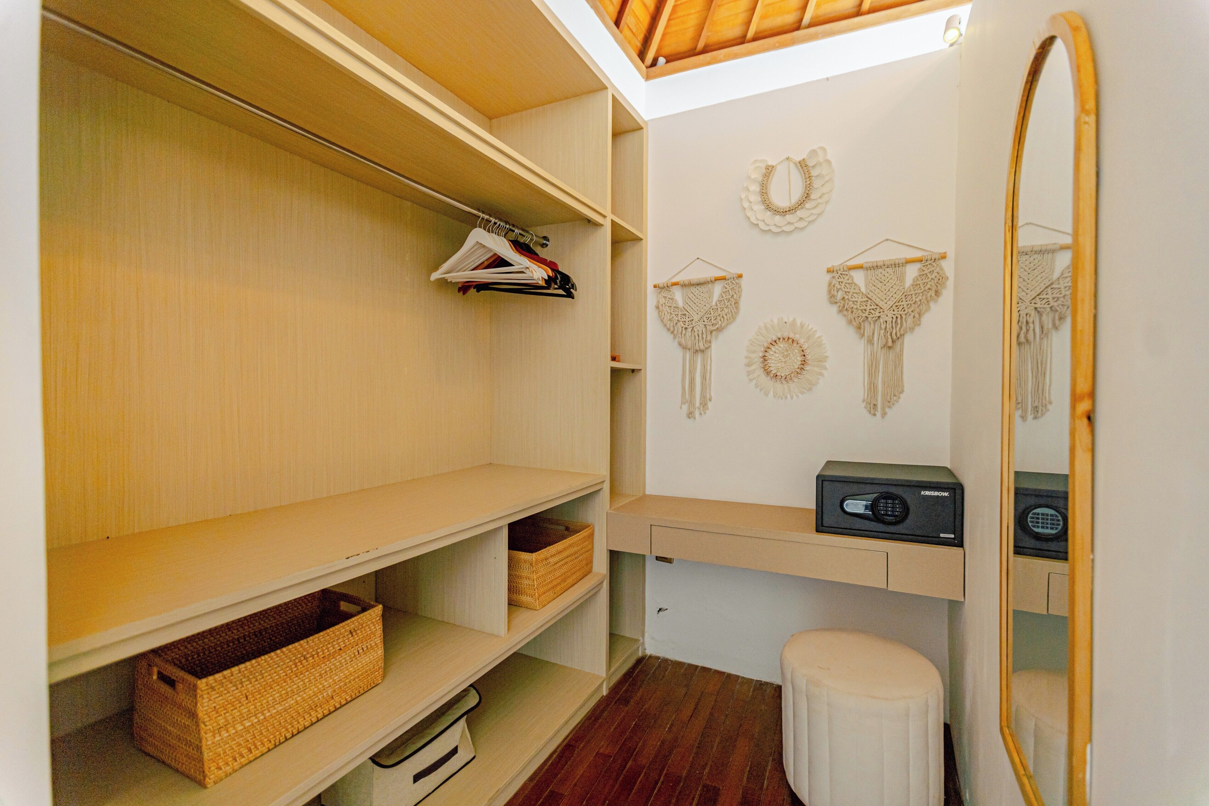 Un dressing ouvert avec des étagères en bois, des paniers en osier et des décorations murales en macramé.