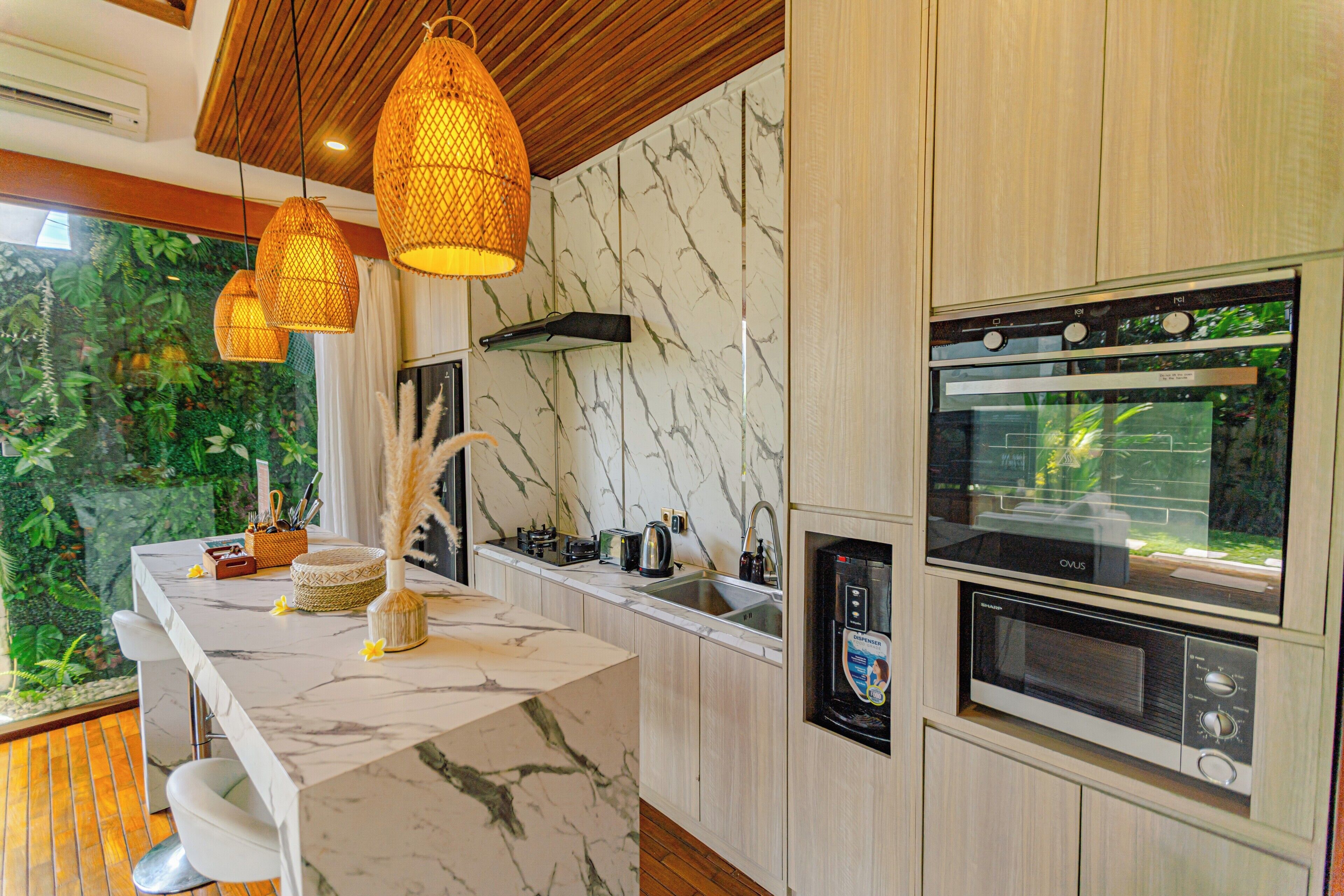 A modern kitchen with marble countertops, built-in appliances, and hanging wicker lights.