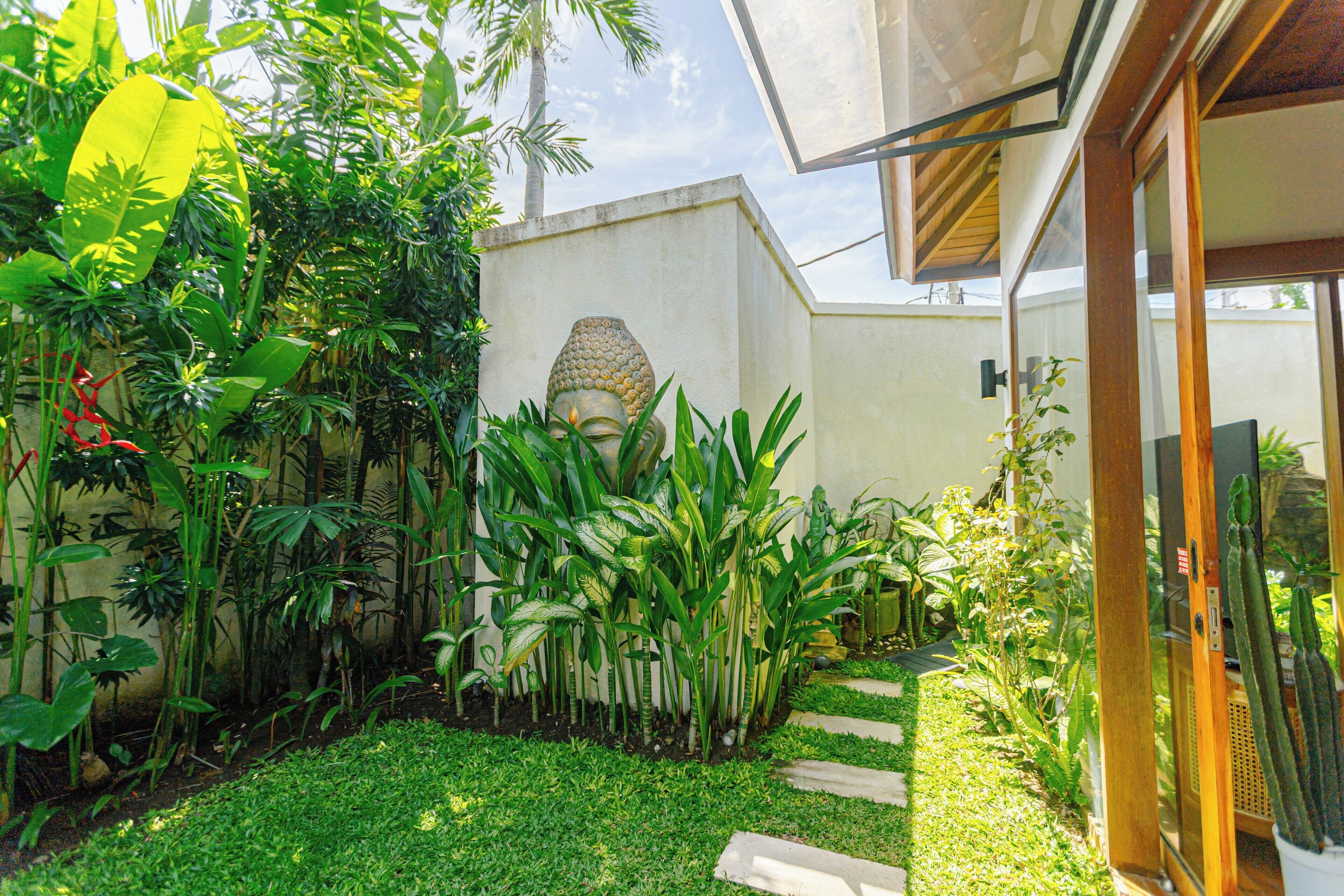 A lush garden with a variety of plants and a stone sculpture.