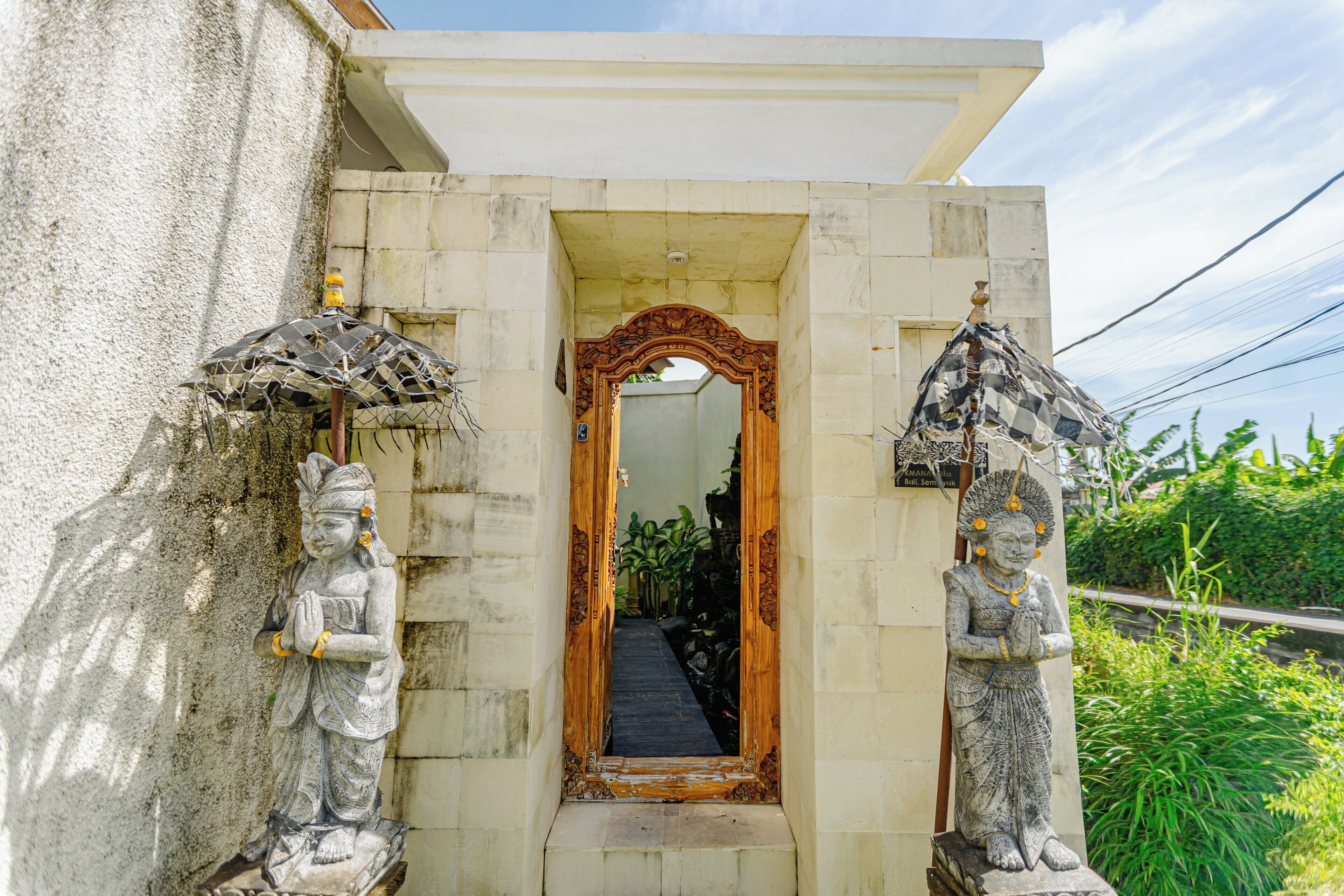 A doorway with a mirror, flanked by statues, leading to a corridor.