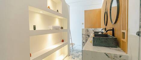 A modern bathroom with a marble sink, wooden paneling, and built-in shelves.