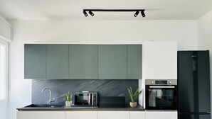 A modern kitchen with dark green cabinets, a black refrigerator, a microwave, and a built-in oven. - Ca D' Amore with free parking (Treviso)