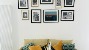 A living room with a sofa, a coffee table, and a wall with framed pictures. - Ca D' Amore with free parking (Treviso)