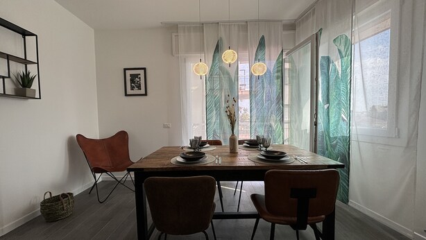 A dining area with a wooden table, four chairs, and a vase with dried flowers. - Ca D' Amore with free parking (Treviso)