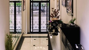 Un hall d’hôtel doté d’une rambarde en verre, d’un comptoir d’accueil noir, d’un lustre et d’œuvres d’art encadrées accrochées aux murs.