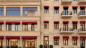 Un hôtel à plusieurs étages, doté d’auvents rouges, de grandes fenêtres et d’une façade bien entretenue.