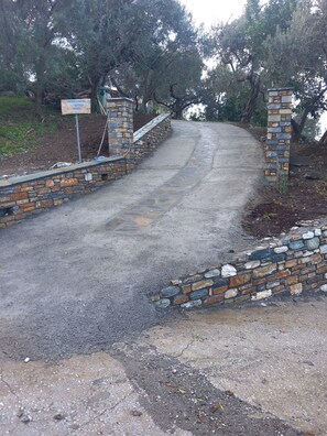 Una carretera pavimentada flanqueada por muros de piedra, que conduce a una puerta de piedra.