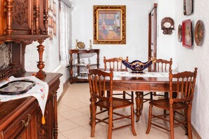 A traditional dining room with a wooden table and four chairs, a decorative bowl, and a framed picture on the wall.