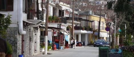 A street view with buildings, a parked car, and a signboard for a cafe.