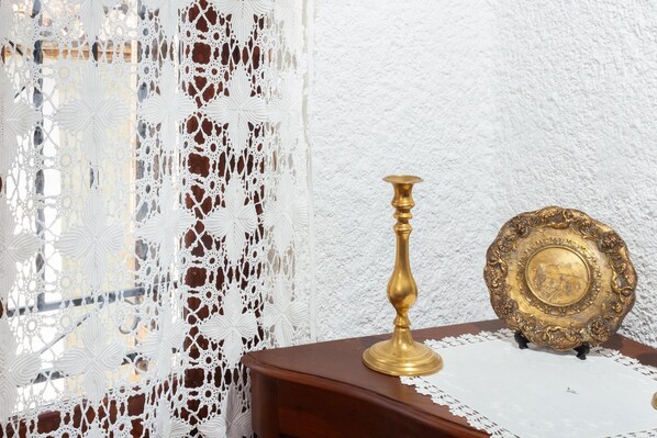 A table with a brass candlestick and a decorative plate on a doily.