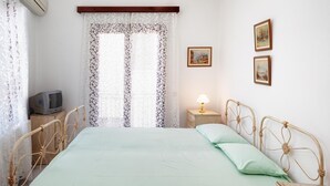A bedroom with a bed, a nightstand, a lamp, a television, and two framed pictures on the wall.