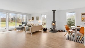 Ein modernes Wohnzimmer mit Kamin, großen Fenstern und einem Essbereich.